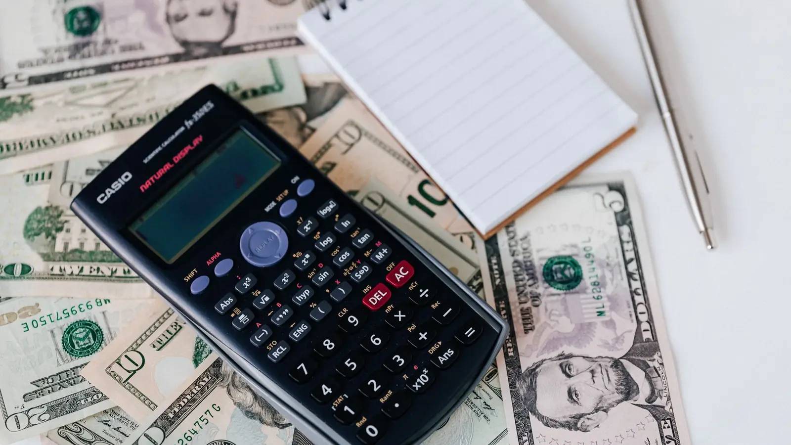 Calculadora, libreta y billetes sobre una mesa para planificar un presupuesto